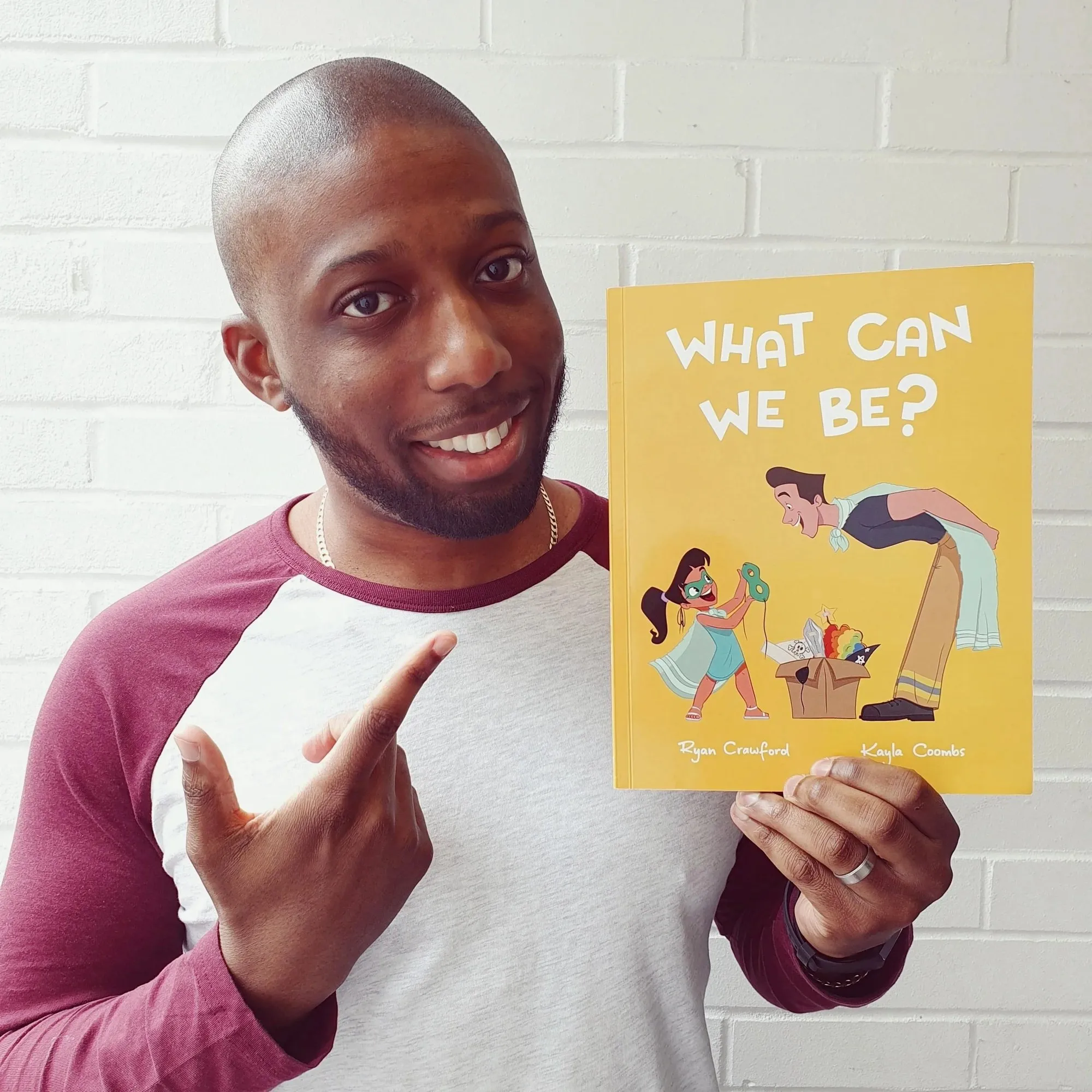 Ryan Crawford holding up a copy of What Can We Be?
